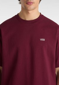 T-shirt en coton bordeaux à manches courtes, col ras du cou, avec le logo "VANS" brodé sur la poitrine gauche. Texture douce, coupe décontractée.