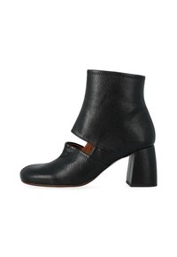 Stivale alla caviglia in pelle nera con punta quadrata, dettagli ritagliati e tacco rettangolare spesso. Superficie testurizzata. Design minimalista.