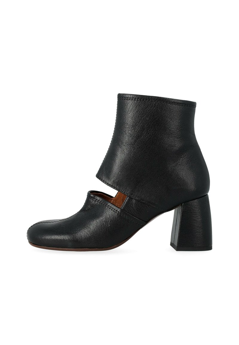 Stivale alla caviglia in pelle nera con punta quadrata, dettagli ritagliati e tacco rettangolare spesso. Superficie testurizzata. Design minimalista.