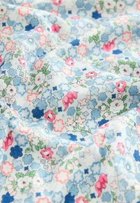 Gaiši zils audums ar ziedu rakstu, kas satur rozā, baltas un zilas ziedus. Mīksta tekstūra ar nelielu spīdumu, krunkaina izskata.