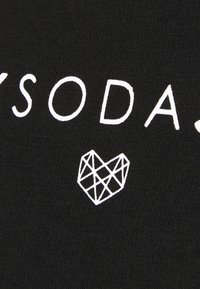 Schwarzer Stoff mit weißem Text "SODA" und einem geometrischen Herzdesign darunter. Glatte Textur, normale Passform und minimalistisches Design.