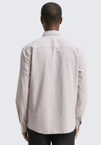 Lichtgrijs overhemd met lange mouwen, voorzien van een button-down kraag, een getailleerde achterkant en knoopmanchetten, gemaakt van een gladde geweven stof.