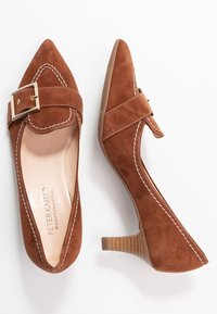 Chaussures à talons hauts en suède marron avec un bout pointu, des coutures blanches décoratives et un accent de boucle sur une sangle. Talon avec texture en bois.