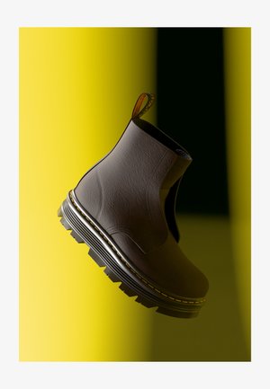 Pruun nahast ankle-boot tekstuuriga pinnaga, elastsete külgdetailidega ja plaatjaksa musta ja kollase tallaga. Tagaküljel on tõmblõng.
