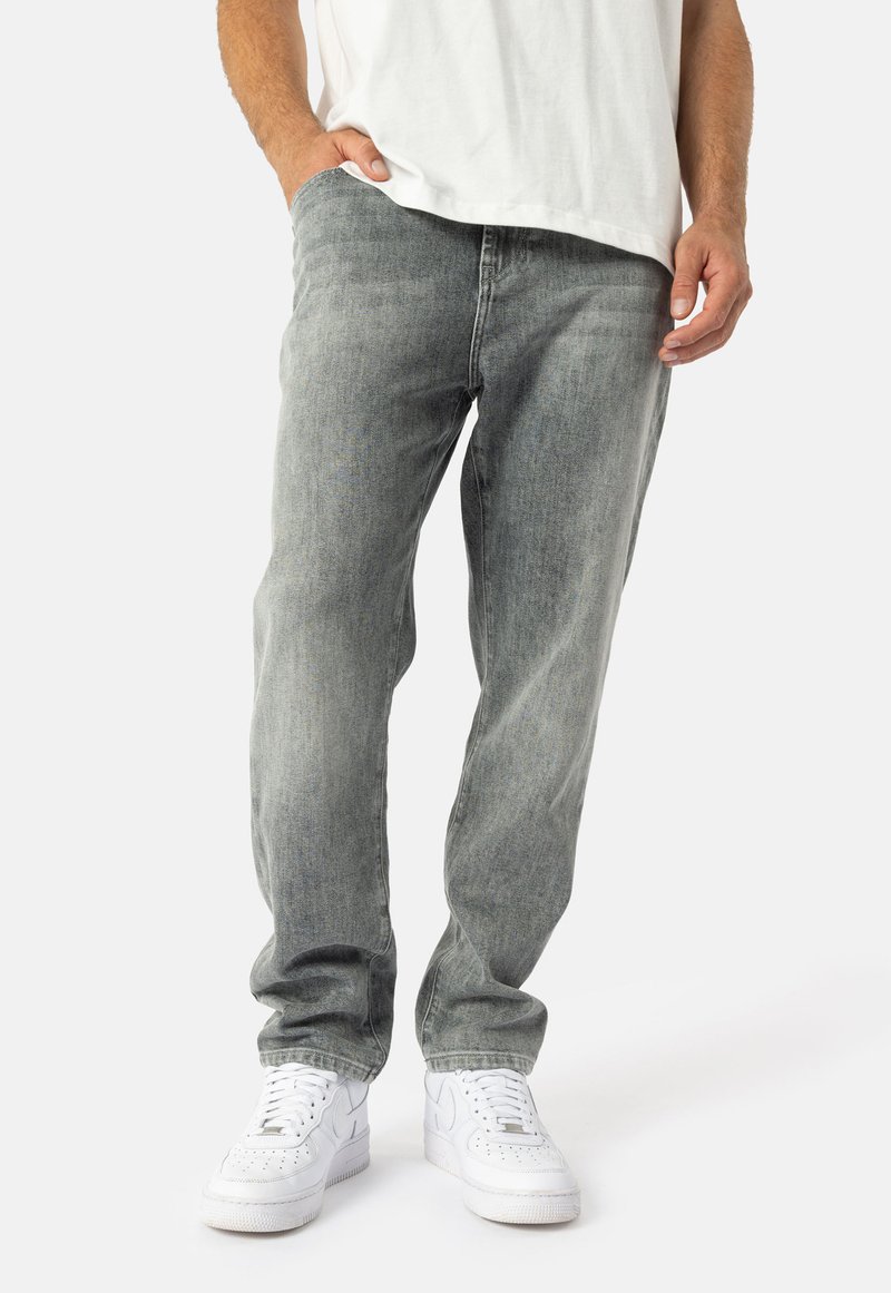 Gaiši pelēki džinsi ar brīvu piegriezumu, kam ir smalki, izbalējuši tekstūras. Apvienoti ar baltiem kedām kontrasta radīšanai.