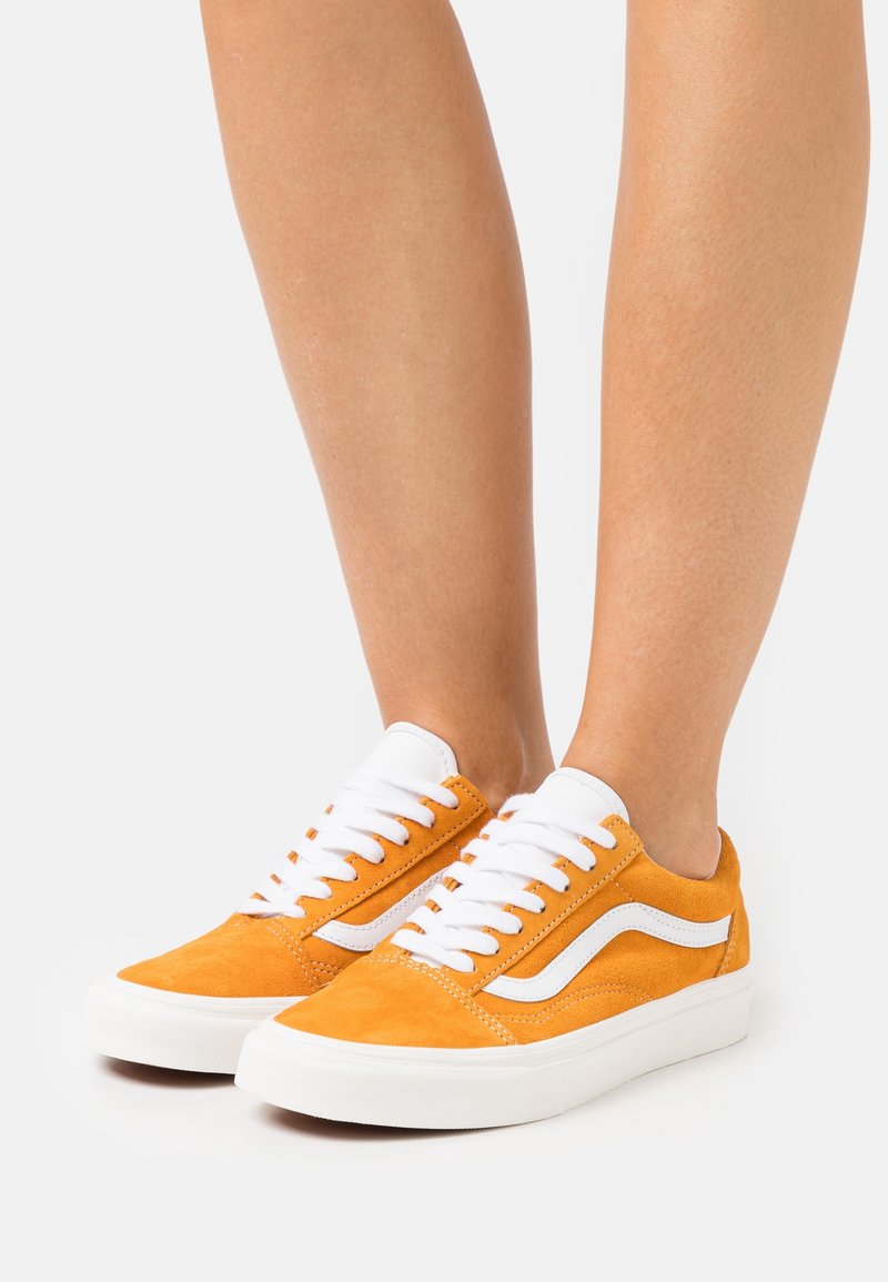 Baskets en daim orange avec lacets blancs et accents latéraux. Bout arrondi, semelle blanche plate, et design classique avec des détails de couture prononcés.