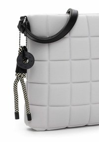 Borsa tote in tessuto bianco trapuntato con manico in pelle nera. Presenta un accento intrecciato e un'etichetta circolare attaccata sul lato.