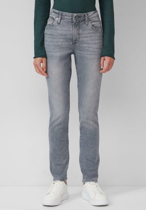 Slim-fit grijze denim jeans met een vervaagde wassing, subtiele slijtage, vijf zakken en een ritsluiting. Gecombineerd met witte sneakers.