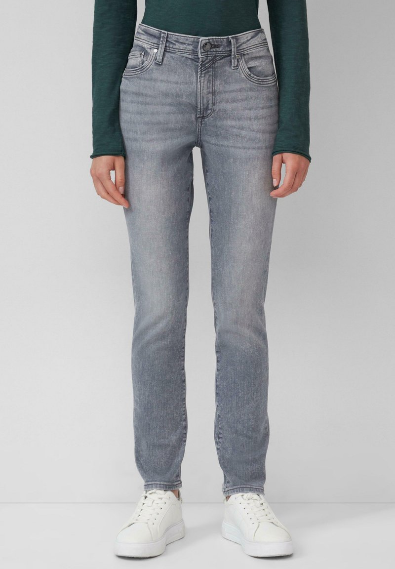Jean en denim gris slim fit avec un lavage délavé, un léger effet de frottement, cinq poches et une fermeture éclair. Associé à des baskets blanches.