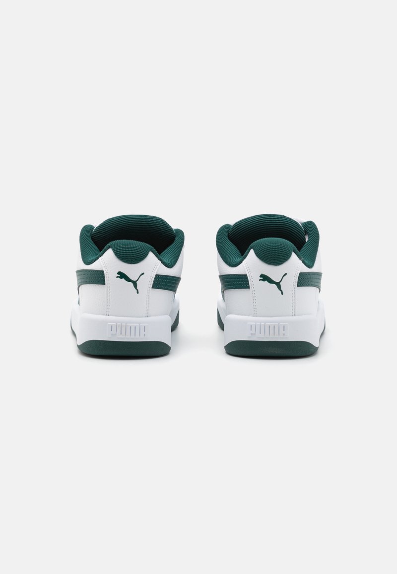 Zapatillas blancas con un collar textil verde y rayas laterales. Suela de goma texturizada con marca blanca en el talón. Diseño minimalista.
