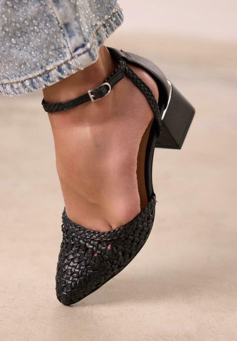 Talons en cuir tissé noir avec un bout pointu et une bride de cheville avec une boucle métallique. Le talon est épais et au design moderne.