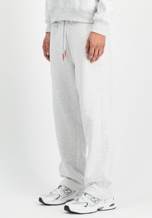 Hellgraue Sweatpants mit weicher Textur, elastischem Bund und Kordelzug. Kombiniert mit weißen und silbernen Turnschuhen.
