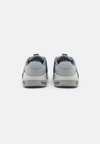 Gray athletic shoes with a textured mesh upper, padded collar, and a sturdy rubber sole featuring a zigzag tread pattern.