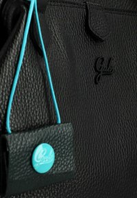 Zwarte leren handtas met een gestructureerde afwerking, voorzien van een turquoise accentlabel en een reliëflogo. Verstelbare turquoise schouderband bevestigd.