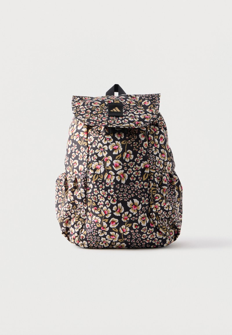 Sac à dos noir avec imprimé floral en rose, blanc et beige, doté d'un rabat sur le dessus et de poches latérales, debout sur un fond blanc.