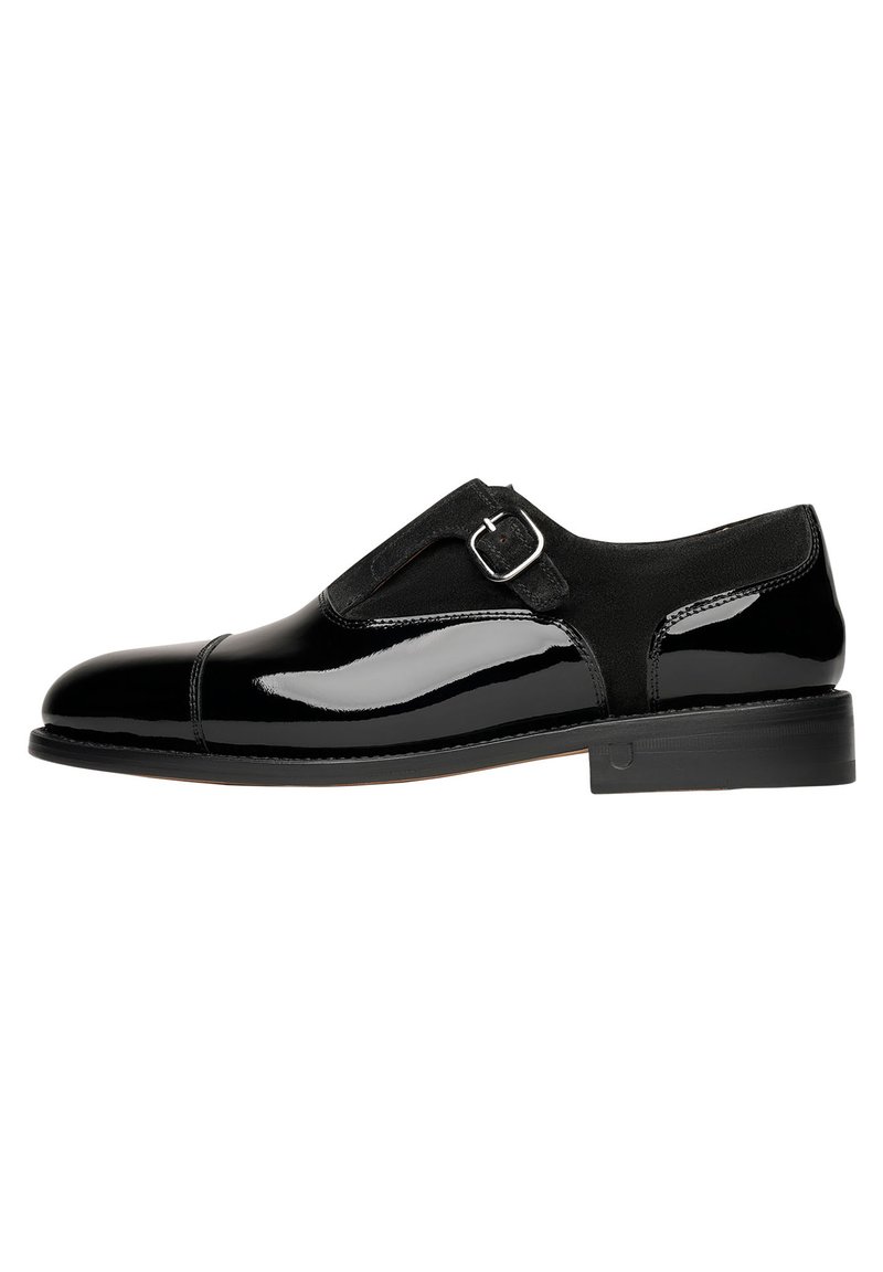 Schwarze Lacklederschuhe mit glatter Oberfläche, ausgestattet mit einem Wildlederriemen und einer silbernen Schnalle, abgerundeter Zehenform und niedrigem, gestapeltem Absatz.