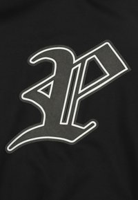 Czarna tkanina z dużym stylizowanym logo w kolorze szarym z białym obramowaniem, przedstawiająca kanciaste kształty i dynamiczne krzywe.