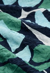 Tissu en coton avec une texture froissée, présentant des formes abstraites dans des nuances de vert, bleu et marine, complétées par des accents blancs.