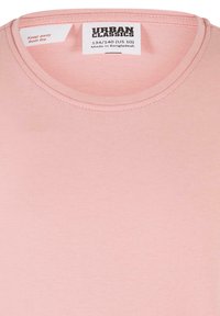 Ljust rosa T-shirt med rund halsringning, tillverkad av mjukt material. Etiketten anger storlek (134/140) och skötselanvisningar.