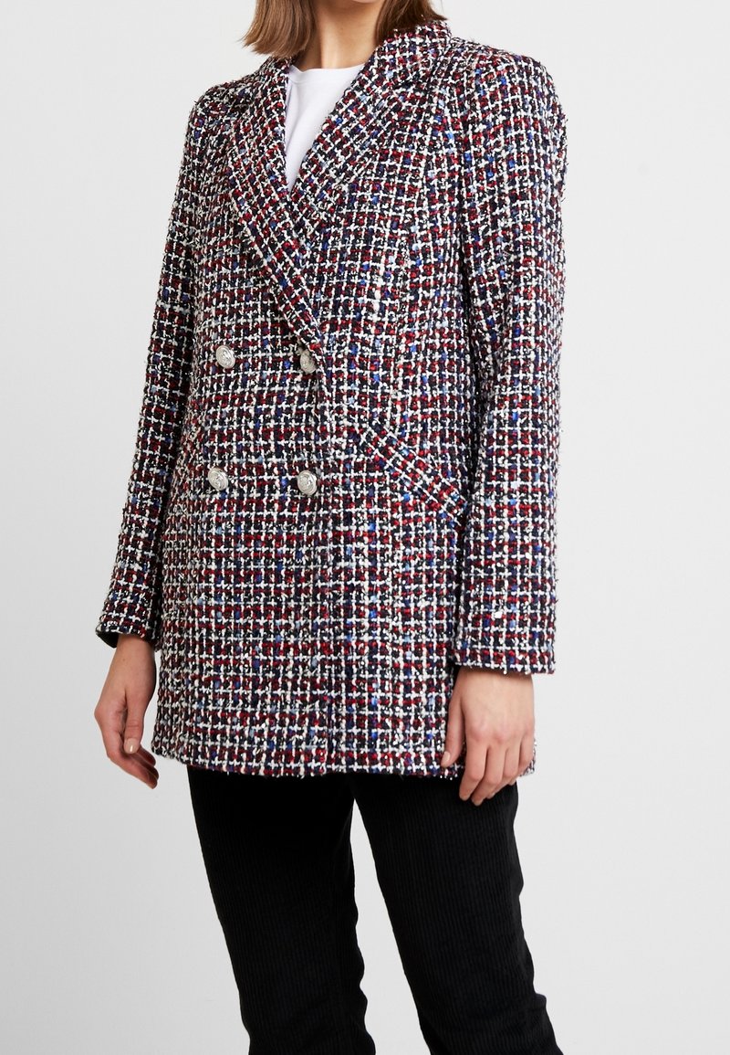 Blazer en tweed à double boutonnage présentant un motif de couleurs rouge, blanc et bleu, avec des boutons métalliques et un col structuré ; surface texturée.