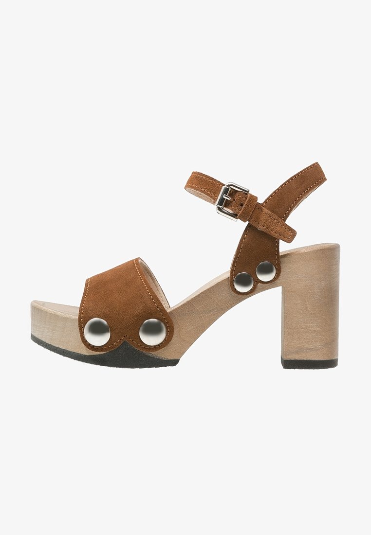 Sandale en suedine marron avec talon en bois, design à bout ouvert, bride de cheville ajustable et accents en métal sur le dessus.