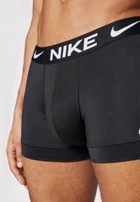 Sorte Nike boxershorts med en kontrasterende hvid logo på taljen, lavet af glat, strækbart stof med en tætsiddende pasform.