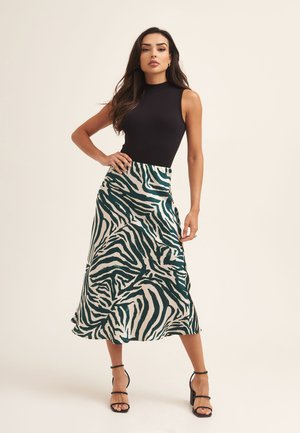 Black sleeveless top paired with a green and white zebra-print satin skirt, featuring a flowing design and layered texture, complemented by black heels.