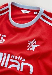 Czerwona koszulka z jasnoniebieskim ściągaczem. Posiada biały nadruk tekstowy oraz grafikę gwiazdy. Slim fit, wykonana z miękkiego materiału.