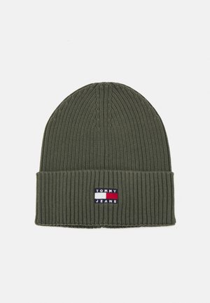 Gorro de punto verde oliva con textura acanalada, que presenta un parche de marca en navy, rojo y blanco en la parte delantera.