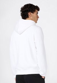 Weißes Kapuzensweatshirt mit lockerem Schnitt, ausgestattet mit einer großzügigen Kapuze, gerippten Bündchen und einer glatten, weichen Textur.