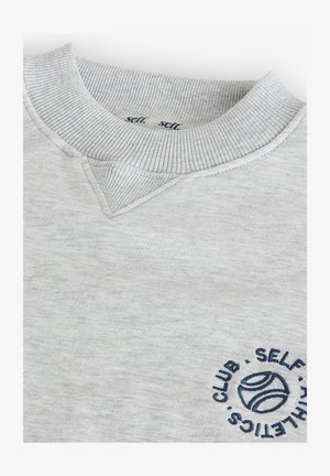 Sweatshirt gris clair avec un col rond côtelé, présentant un petit logo de balle de tennis bleue et du texte sur la poitrine, texture de tissu lisse.