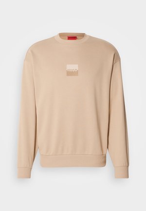 Beige sweatshirt med rund halsudskæring og ribstrikkede ærmekanter. Har et lille firkantet logo i lyse farver foran. Blød, glat tekstur.