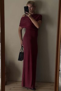 Burgundy off-shoulder-mekko, jossa on rypytettyjä yksityiskohtia, pitkä siluetti ja sileä rakenne. Yhdistettynä pieneen mustaan käsilaukkuun ja korkokenkiin.