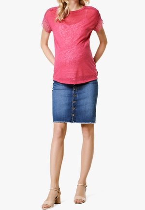 Rosa kurzärmliges Oberteil mit Spitzenverzierungen, kombiniert mit einem Jeans-Bleistiftrock mit vorderen Knöpfen und fransigem Saum. Beigefarbene Blockabsatzsandalen.