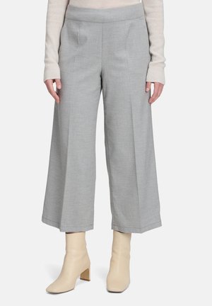 Graue Weite-Hosen mit glatter Textur, die vorne Falten und einen bequemen Bund besitzen, kombiniert mit hellbeigen Knöchelstiefeln.
