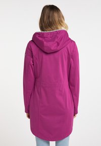 Jachetă lungă roz cu glugă, fabricată dintr-un material moale, având talie ajustată, fante la spate și un tiv curbat. Design minimalist, fără hardware vizibil.