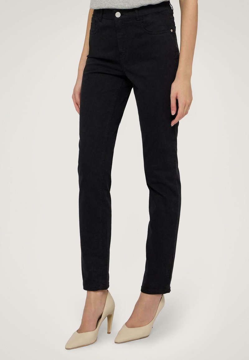 Svarta skinny jeans med hög midja, framfickor och en slät textur. Har en knappstängning och subtila sömnadsdetaljer.