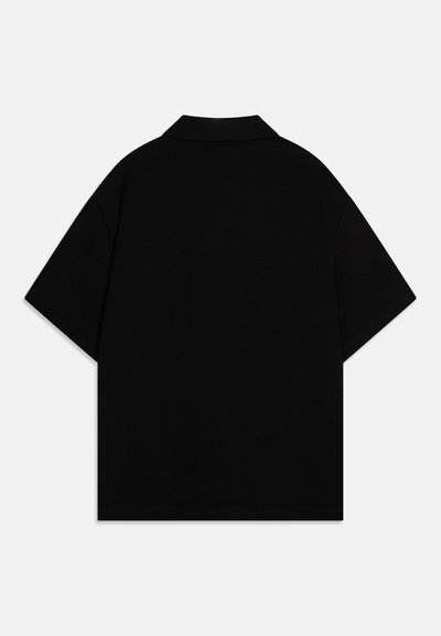 Svart kortärmad polo T-shirt med platt krage och oversized passform, tillverkad av mjukt, lätt tyg. Ingen synlig branding eller accenter.