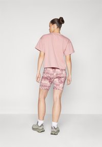 Rosa cropped t-skjorte, matchende rosa kamuflasje sykkelshorts og grå joggesko. Enkelt design, mykt stoff og avslappet passform.