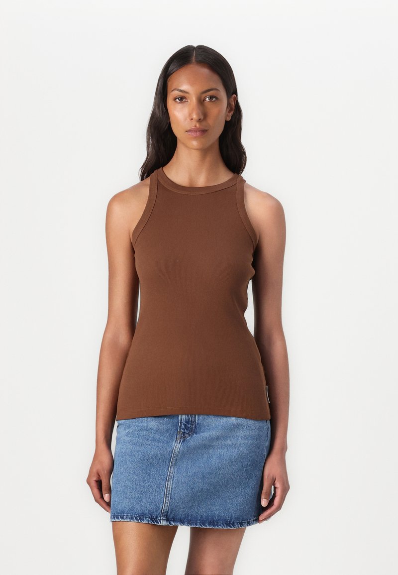 Bruine geribde tanktop met een hoge halslijn en brede schouderbanden, gecombineerd met een lichtblauwe denim mini-jurk. Soepele textuur, strak ontwerp.