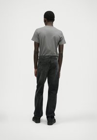 Šedé tričko, čierne džínsy a čierne topánky. Džínsy majú päť vreciek s zadnými vreckami. Jednoduchý a ležérny outfit.