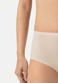 Beige hoog geribbelde slips gemaakt van zachte, lichte stof. Kenmerkt een naadloos ontwerp met zachte randen en een minimalistische stijl.