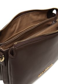 Borsa a mano in pelle marrone con una superficie liscia, chiusura con zip e hardware in tonalità dorata. L'interno presenta una foderatura marrone chiaro e scomparti.