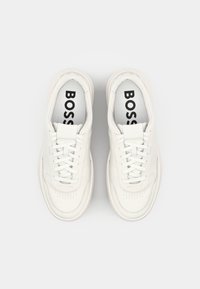 White leather sneakers with perforated detailing, round toe, flat laces, and logo on the insole. Cushioned sole with a textured finish.