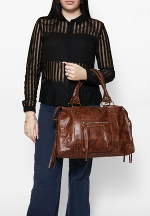 Braune Lederhandtasche mit strukturierter Form, sichtbaren strukturierten Akzenten, abnehmbarem Tragegurt und vorderer Reißverschlusstasche. Die Griffe sind robust und mit Metallbeschlägen versehen.