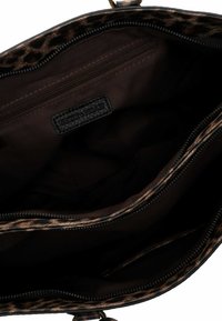 Sac à main en imprimé léopard brun avec une texture lisse, des compartiments zippés et un intérieur sombre comportant une petite poche et une étiquette de marque.