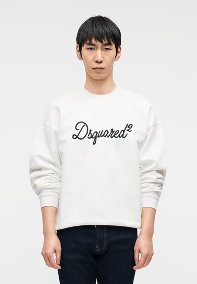 Λευκό φούτερ με μαύρο κεντημένο λογότυπο "Dsquared²", με στρογγυλή λαιμόκοψη και μακριά μανίκια, συνδυασμένο με σκούρο μπλε τζιν.