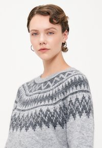 Szürke kötött pulóver, amely hagyományos Fair Isle mintával készült sötétszürke árnyalatokban, kerek nyakkivágással és puha, texturált anyaggal.