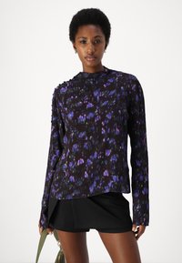 Long-sleeve blouse in black with purple and blue floral pattern. Lightweight fabric with a high neckline and subtle button details on sleeves.