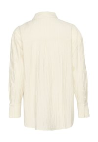 Witte textuur shirt met een kraag, lange mouwen en knoopmanchetten; heeft een licht gekreukte stof en een detail op de rug.